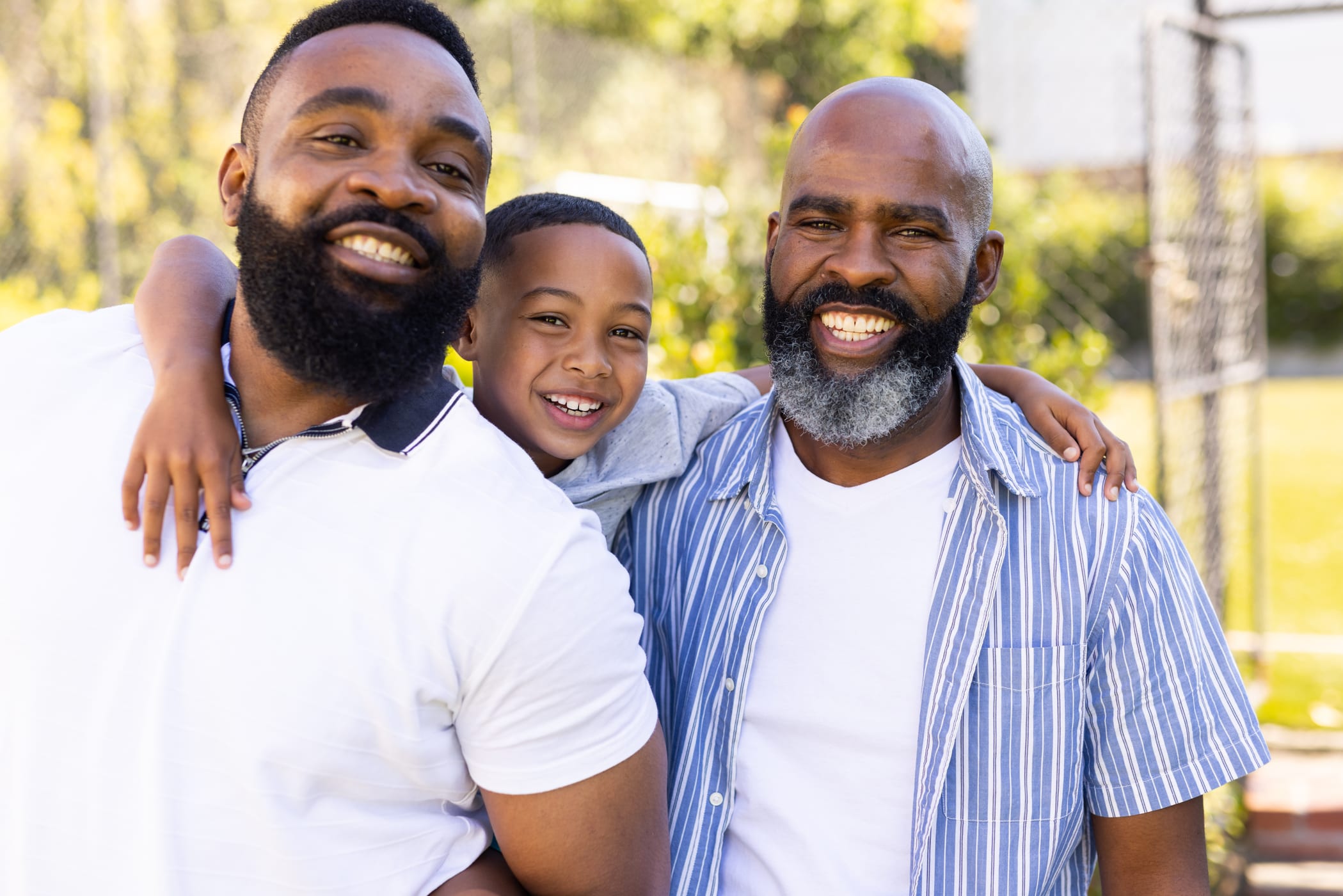 Smiling child with two adult men outdoors